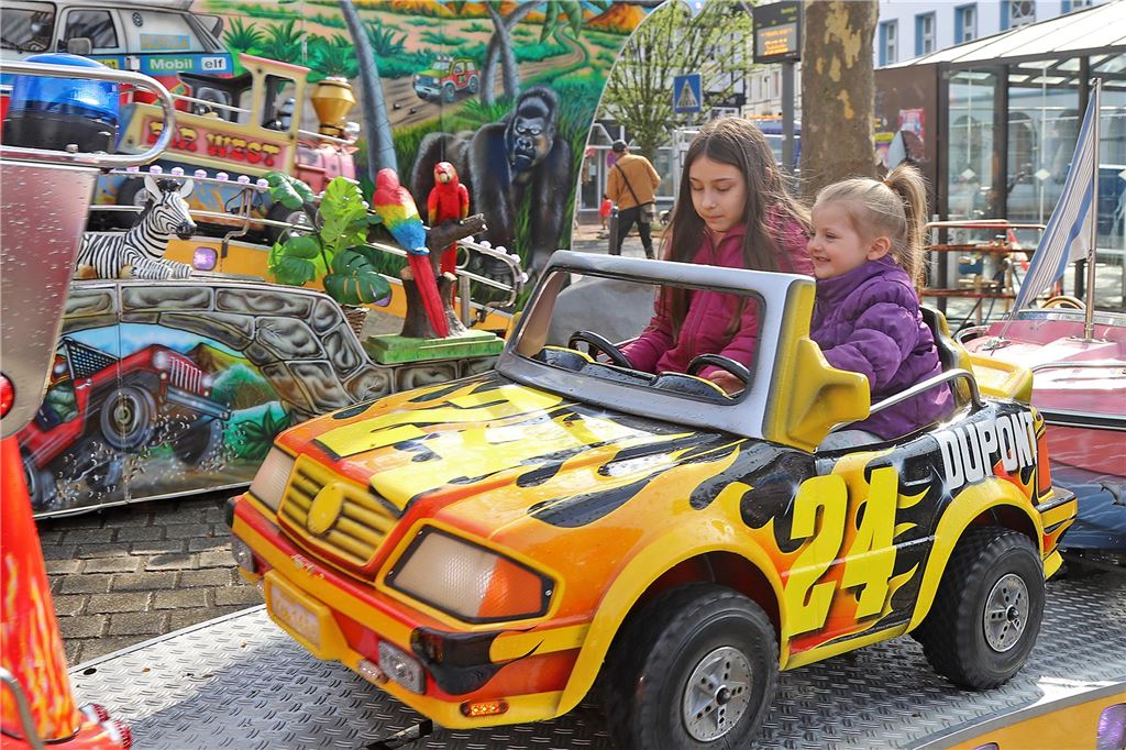 Zwei Mädchen sitzen in einem Kirmes-Auto. 