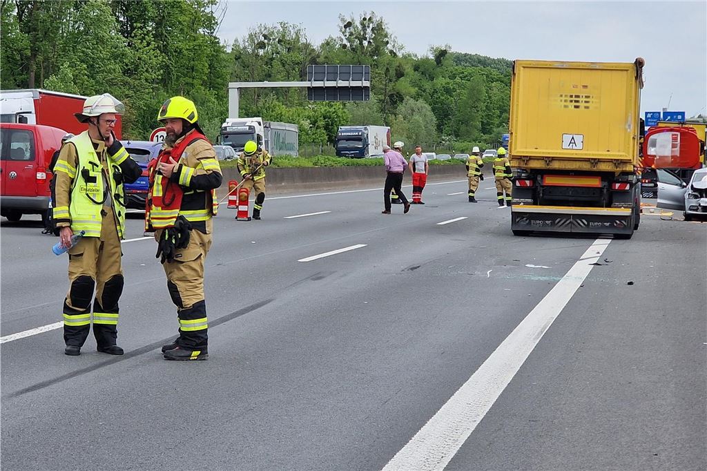Feuerwehrleute stehen auf der Autobahn.
