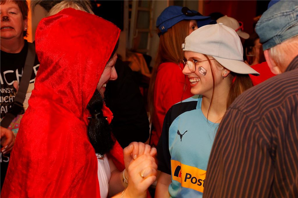 Eine Frau im Rotkäppchen-Kostüm und eine im Postbank-Shirt lachen sich an.
